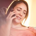 Twisted Electric female electrician - woman on the phone looking happy wearing a peach-coloured top