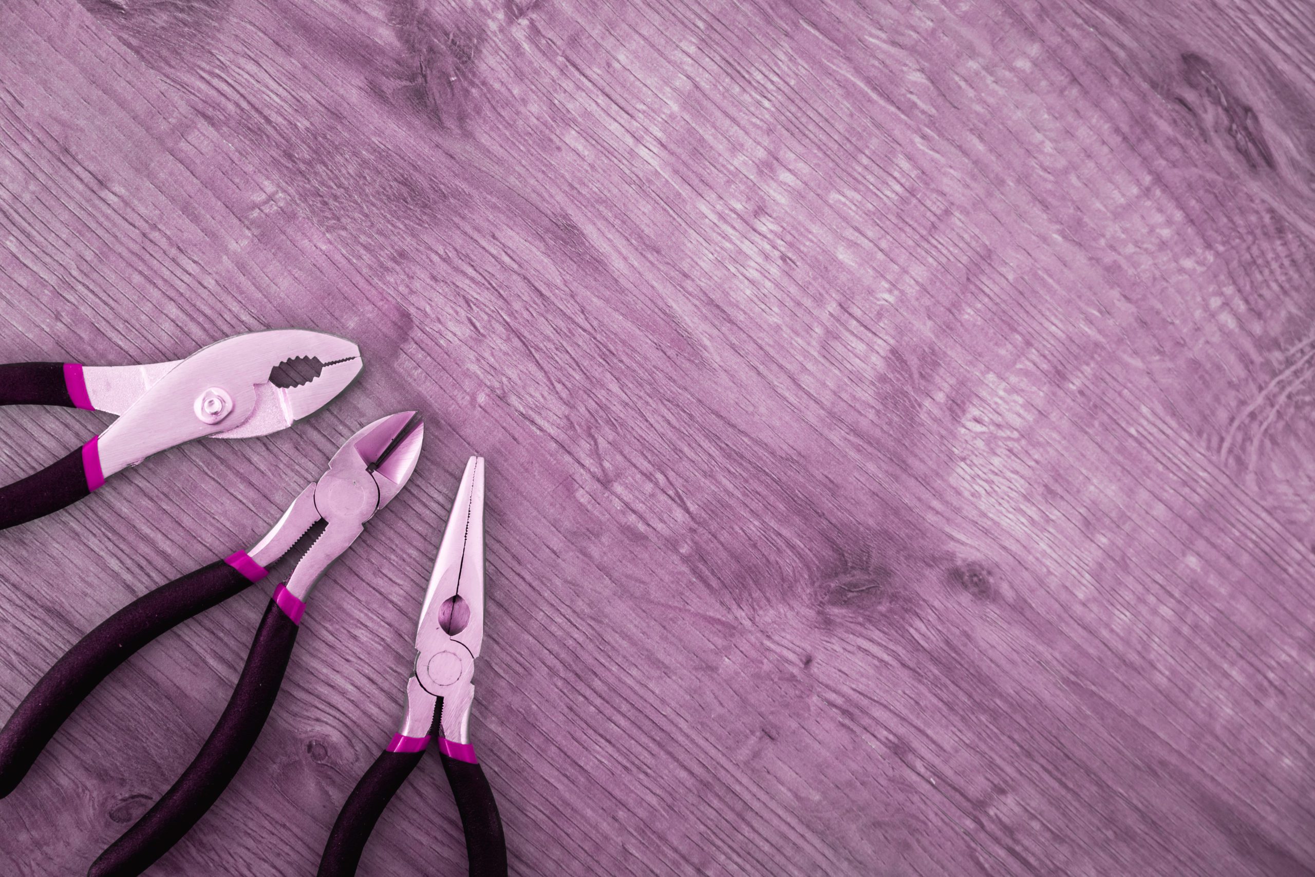 Pink filtered image with pliers etc. on a wooden floor - electrician services greater moncton