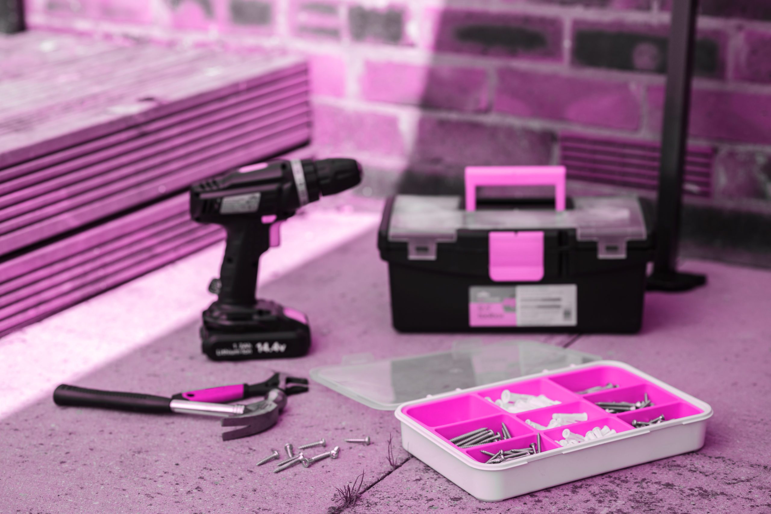Pink filtered image of a drill, toolbox and other tools near wall - electrical contractor moncton