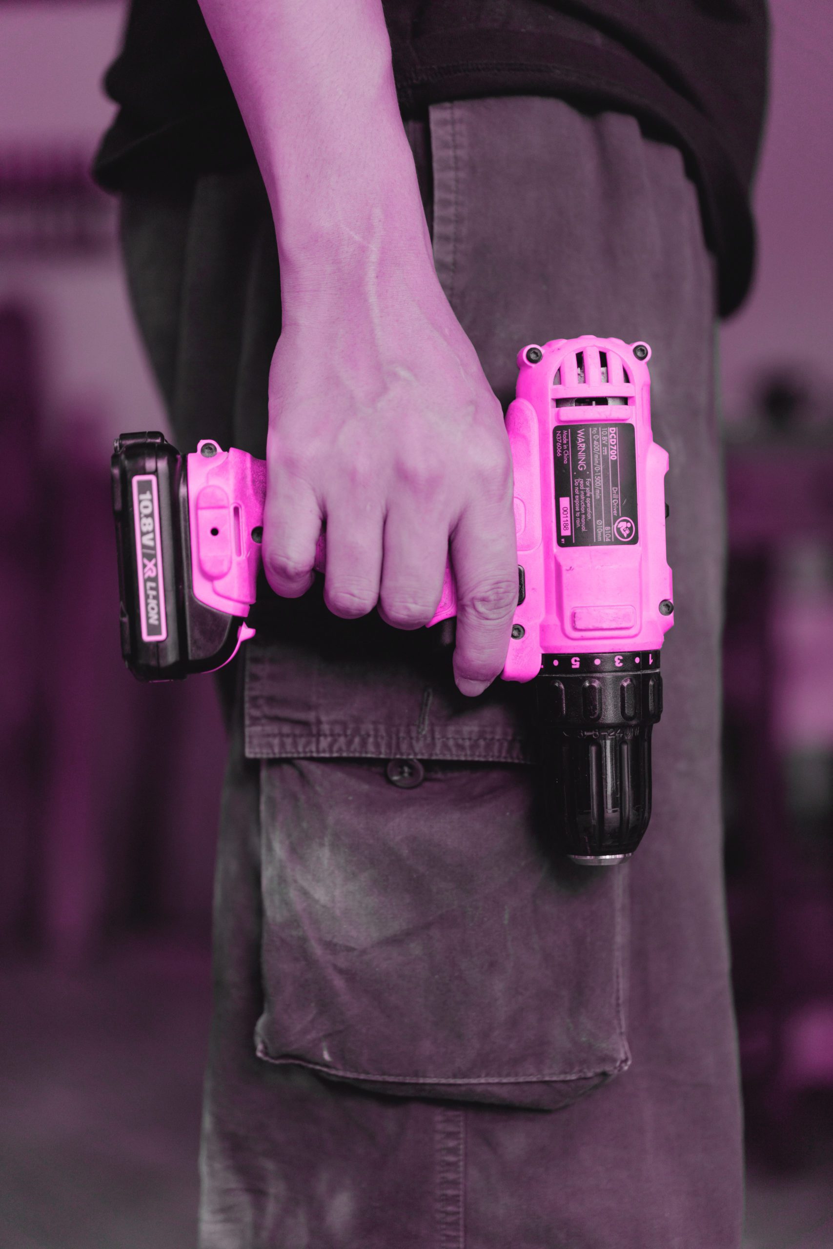Pink filtered image of a man holding a drill by the side of his leg - certified female electrician atlantic canada