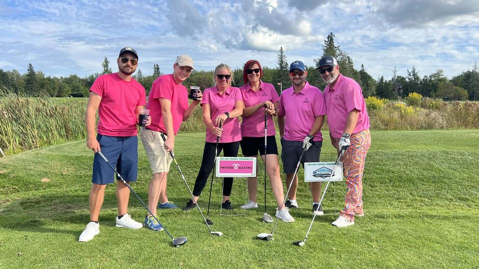 Tina Young, a female and 4 males in hot pink Twisted Electric t-shirts with golf clubs on a course for charity event